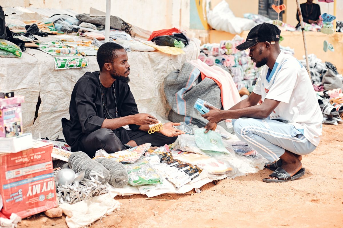 Two men trading goods at an outdoor market